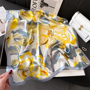 Détail de l'imprimé floral abstrait jaune et bleu sur un foulard carré en satin de soie