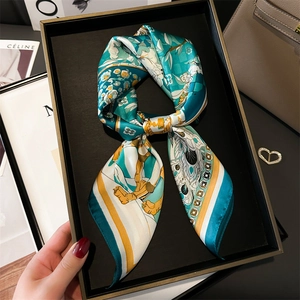 Close-up of silk landscape scarf with floral motifs tied in a bow in a black gift box
