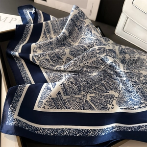 Detail of silk-like scarf with map print neatly folded in a premium leather tray