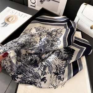 Classic landscape print silk scarf folded in a black tray with elegant bag and magazine