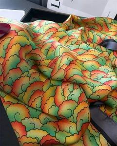 Gros plan d'un foulard en satin coloré avec motif de nuages vert et orange et bord noir