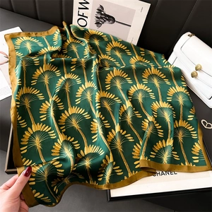 Détail d'un foulard en soie avec motif palmier doré et texture élégante vert foncé