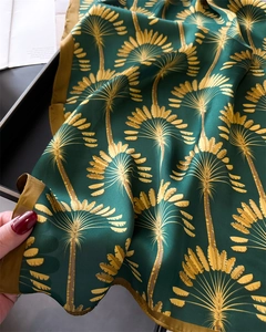 Détail de la texture satinée lisse et du motif de palmier jaune sur un foulard vert foncé