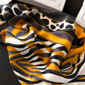 Close-up of silky leopard print scarf with yellow geometric patterns and chain details
