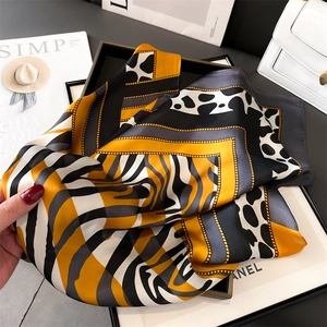Detail of silk-like scarf featuring leopard and zebra patterns with golden chain border