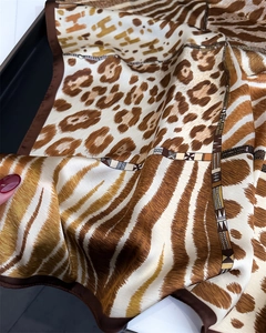 Close-up of leopard and zebra print silk scarf with H-pattern and geometric border