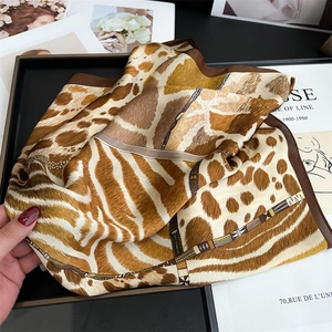 Detail of soft silk-like scarf featuring leopard and zebra prints with geometric borders