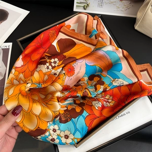 Detail of silk satin scarf with vibrant peony and dahlia patterns on a black display tray