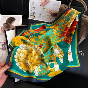 Peony silk square scarf with floral print and turquoise border draped on a handbag