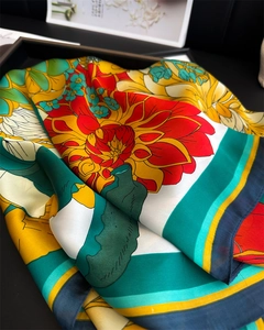 Macro detail of silk scarf featuring vibrant red peony floral patterns on elegant tray