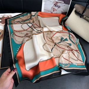 Dettaglio della trama di un foulard in seta con stampa a catena su una borsa beige