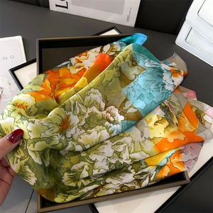 Macro detail of glossy peony floral print silk scarf displayed on a luxury black tray