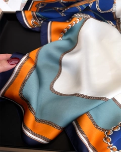 Dettaglio macro della trama in raso setoso e della stampa a catena dorata sul foulard