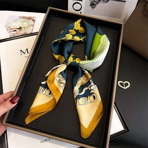 Detailed close-up of a twilly silk scarf tied in a bow with ginkgo and equestrian patterns