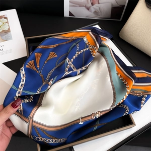 Dettaglio di un lussuoso foulard in seta con stampa a catena blu su borsa in pelle