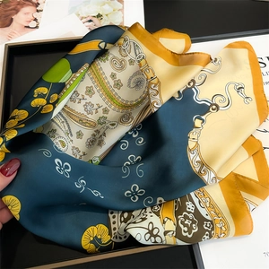 Detailed macro view of the intricate paisley and floral patterns on the silk-like square scarf