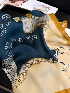 Close-up of silk scarf with paisley and chain patterns displayed on an elegant tray