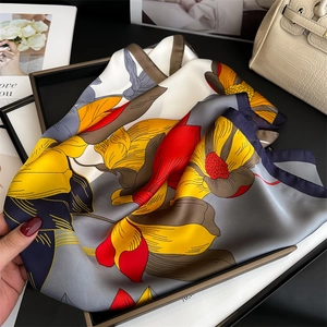 Detail of elegant floral silk scarf with bold prints displayed on a luxury black tray