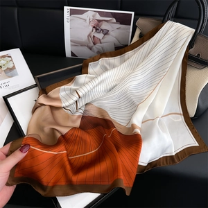 Elegant geometric floral silk scarf with warm orange and brown tones in satin finish
