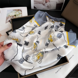 Dettaglio di un elegante foulard in raso floreale con fiori gialli in una confezione regalo