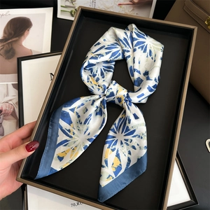 Elegant blue and white silk-like square scarf with floral pattern on black tray