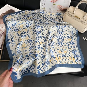 Close-up of floral silk scarf with blue border on a luxury accessory display tray