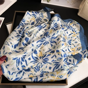 Detailed view of silk square scarf with geometric star print on a black tray