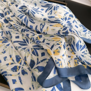 Close-up of geometric silk scarf with blue, white, and yellow patterns and refined hem