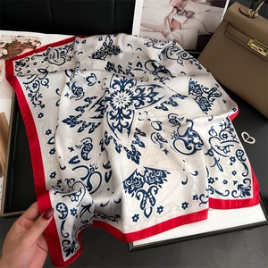 Detail of paisley silk square scarf with red border and blue patterns on white fabric