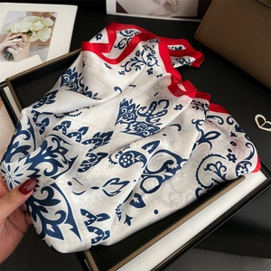 Detail of silk scarf with paisley pattern and red border displayed in a gift box