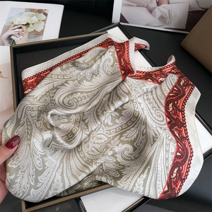 Dettaglio di sciarpa in seta vintage con stampa paisley verde e bordo a contrasto