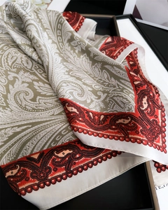 Dettaglio macro di sciarpa in seta vintage con motivi paisley e eleganti bordi rossi