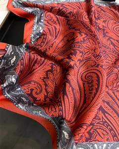 Dettaglio della sciarpa in seta con stampa paisley in vivaci colori arancio e viola