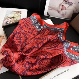 Dettaglio del foulard di seta vintage con motivi paisley e bordo floreale in toni arancio