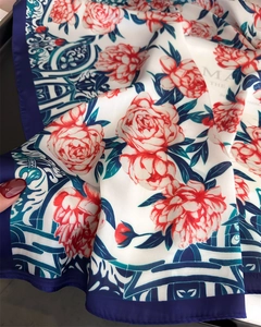 Detail of red floral print and navy blue vintage border on silk texture square scarf