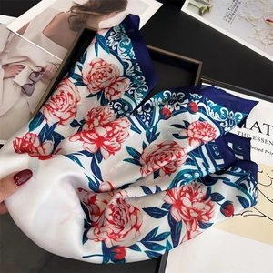 Detailed view of red peony print on silk scarf with elegant blue floral patterns
