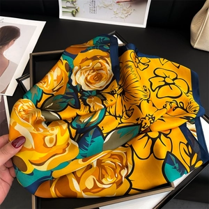 Detail of floral silk-feel scarf with yellow roses and navy blue border in a stylish setup