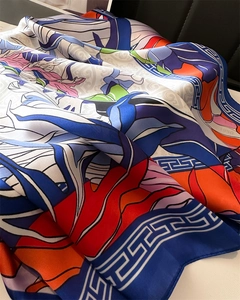 Close-up of silk-feel scarf featuring Greek Key patterns and vibrant floral prints