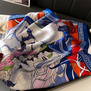 Detail of high-saturation floral satin scarf with blue geometric border and silk texture