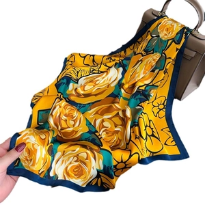 Elegant yellow rose silk scarf with navy border draped over a designer bag