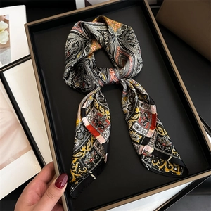Detailed view of silk scarf with paisley patterns in black, gold, and red on a tray