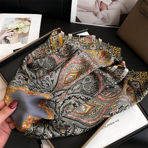 Detailed view of paisley silk scarf with satin finish on a display tray