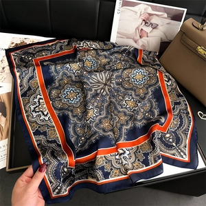 Detail of navy blue silk-like square scarf with vintage paisley patterns and orange borders