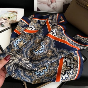Detailed close-up of paisley pattern silk scarf with navy blue and orange silk texture