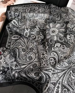Close-up of black and white paisley pattern on luxury satin square silk scarf texture