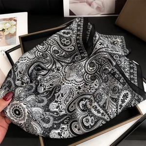 Detailed view of paisley silk scarf with black borders and elegant satin texture