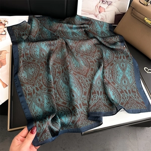 Detail of teal and brown paisley pattern silk scarf on elegant flat lay background