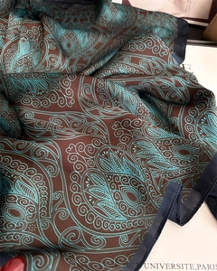 Detail of silk-like paisley scarf with intricate blue patterns and rich coffee brown base