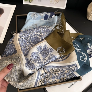 Close-up of silk scarf with blue baroque floral pattern in luxury black gift box
