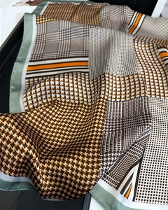 Detailed view of the soft satin houndstooth square scarf with vibrant orange and brown tones